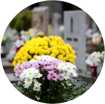 Yellow, white, and purple flowers sit on a grave at a cemetery.