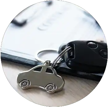 A car key is attached to a car-shaped silver keychain and rests on top of a clipboard.