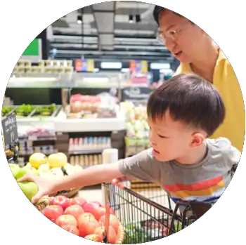 An Asian man is in a grocery store with his young son, who sits in a shopping cart.