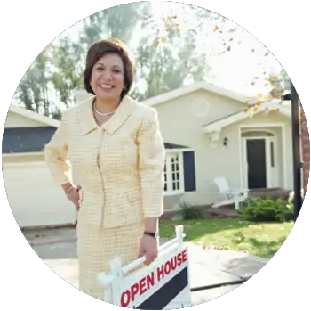 A tan middle-aged female real estate agent holds a sign that says Open House in front of a house.