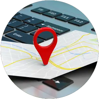 A red map pointer is pointing to a location on an open map on top of a laptop keyboard.